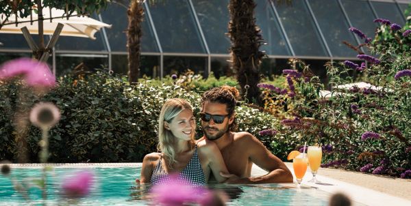 Ein Mann und eine Frau stehen mit Cocktails im Außenpool vom Paradise Beach