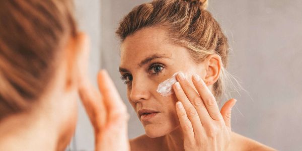 Eine Frau trägt sich eine Gesichtsmaske auf