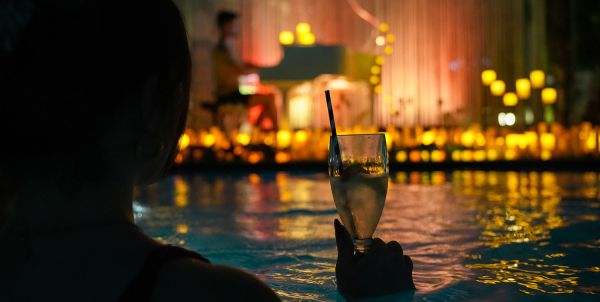 Silhouette of a person in water with cocktail, candlelight in the background