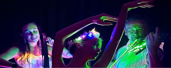 Two people play instruments in the dark and glow