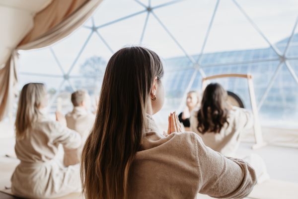 Frauen meditieren vor großer Glasfront