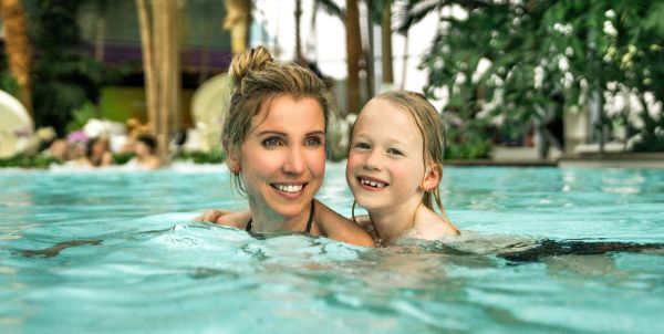 Eine Frau schwimmt mit ihrer kleinen Tochter im Palmenparadies
