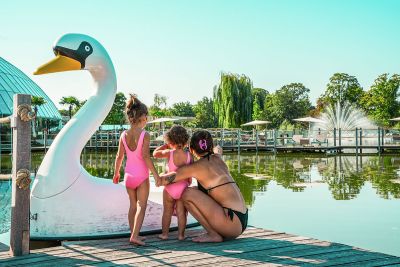 Eine Familie steht an einem Schwanen-Boot an einem See