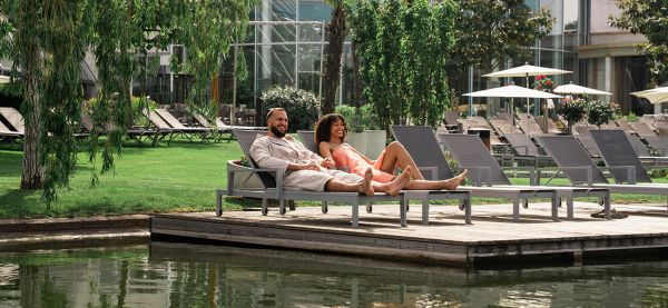 Eine Frau und ein Mann liegen auf einer Liege am Wasser