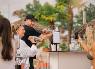 Zwei Personen mixen an einem Strand Cocktails