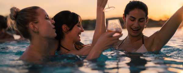 Drei Frauen tanzen und lachen im Pool 