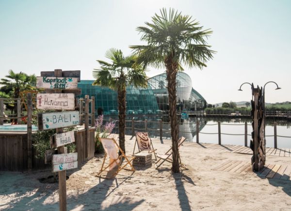 Strand und Palmen vor einem See und einer Therme