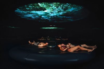 Guests lie back and relax on a circular lounging area beneath a large projected globe on the ceiling.
