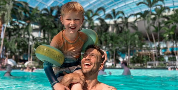 Eine Familie schwimmt im Pool unter Palmen